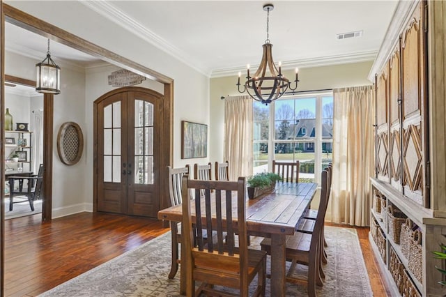 dining room with visible vents, wood finished floors, french doors, arched walkways, and an inviting chandelier