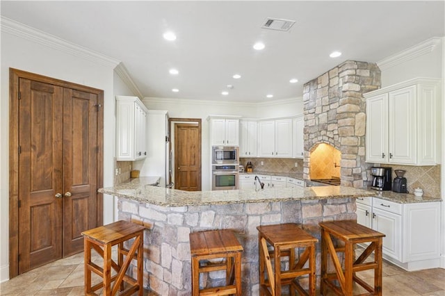 kitchen with a peninsula, a kitchen breakfast bar, visible vents, and stainless steel appliances