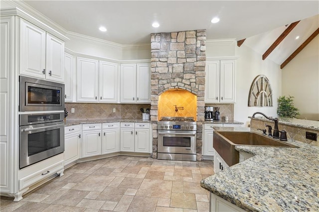 kitchen featuring white cabinetry, backsplash, appliances with stainless steel finishes, and a sink