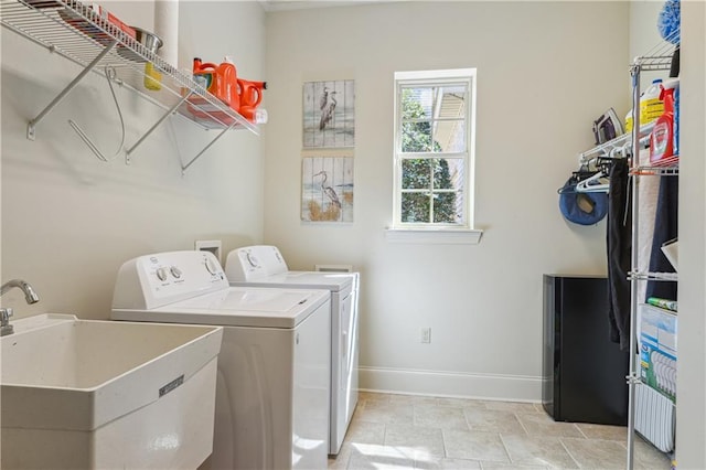 laundry room with washer and clothes dryer, laundry area, baseboards, and a sink