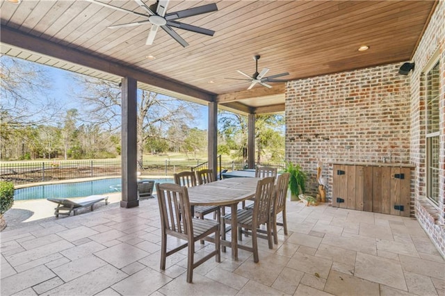 view of patio featuring outdoor dining space, fence, a fenced in pool, and a ceiling fan