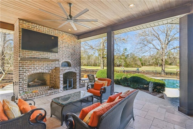 view of patio / terrace with an outdoor living space with a fireplace, fence, and ceiling fan