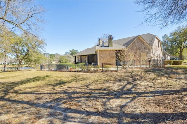 back of property with a chimney, a yard, and fence