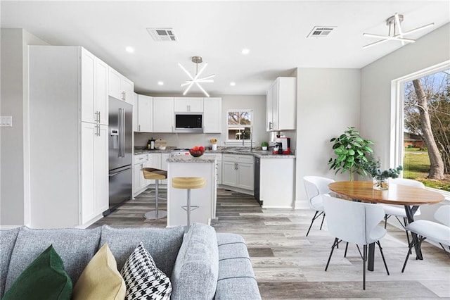 kitchen with visible vents, built in microwave, open floor plan, a wealth of natural light, and high quality fridge