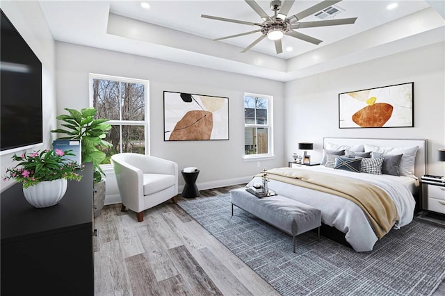 bedroom featuring visible vents, baseboards, light wood-type flooring, recessed lighting, and a raised ceiling