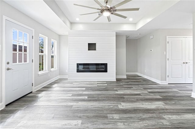 unfurnished living room with a ceiling fan, wood finished floors, and baseboards