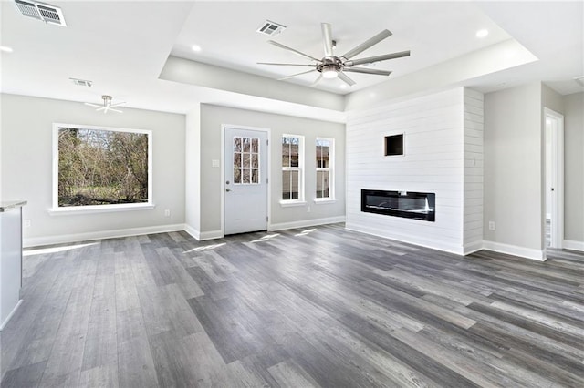 unfurnished living room featuring visible vents, baseboards, a raised ceiling, and ceiling fan