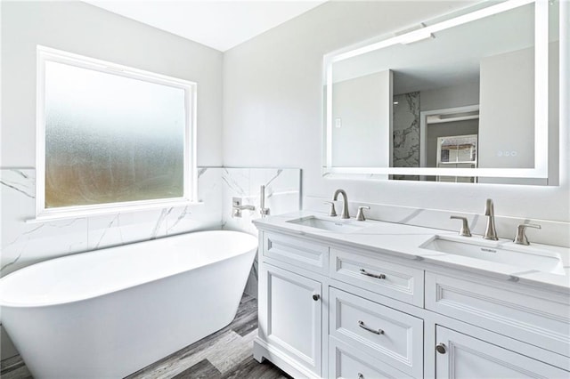 full bathroom featuring a sink, a freestanding tub, wood finished floors, and double vanity