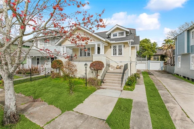 bungalow-style house featuring driveway, a detached garage, a porch, fence, and a front yard