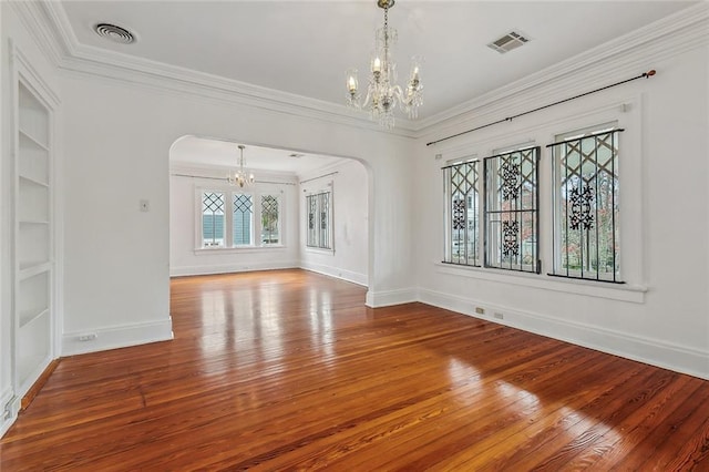 spare room with arched walkways, visible vents, built in shelves, and an inviting chandelier