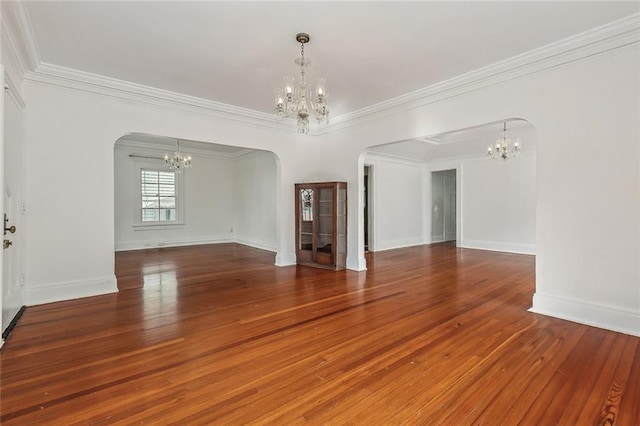 unfurnished room with arched walkways, crown molding, an inviting chandelier, and hardwood / wood-style floors