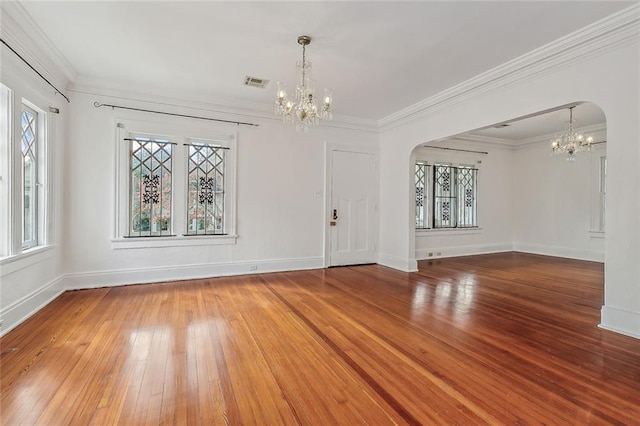 spare room with visible vents, a chandelier, ornamental molding, arched walkways, and wood-type flooring