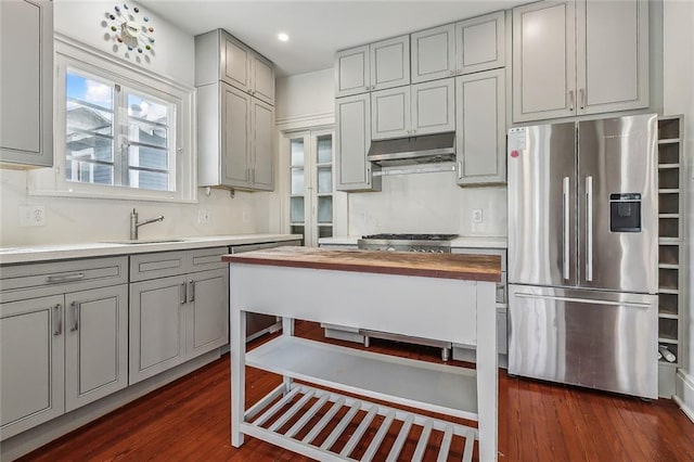 kitchen featuring under cabinet range hood, appliances with stainless steel finishes, butcher block counters, and gray cabinetry