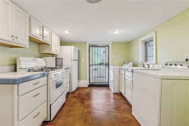 kitchen featuring finished concrete flooring, white appliances, white cabinets, light countertops, and washing machine and clothes dryer