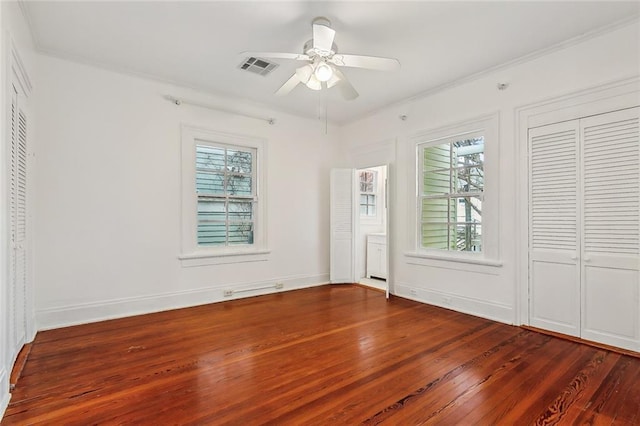 unfurnished bedroom featuring visible vents, ornamental molding, baseboards, and wood finished floors