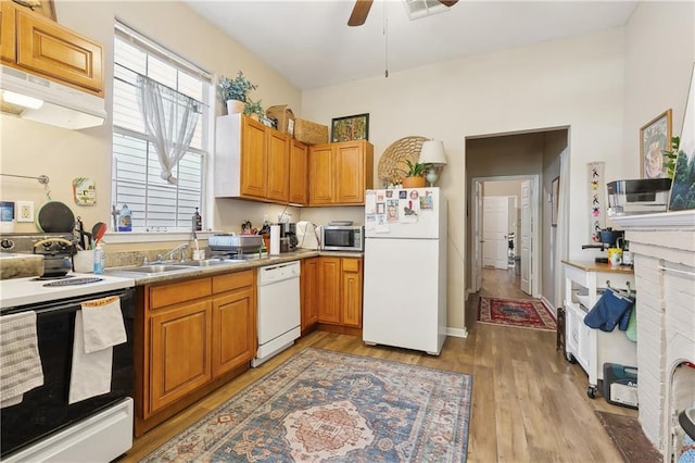 kitchen with white appliances, a sink, ceiling fan, light wood finished floors, and under cabinet range hood