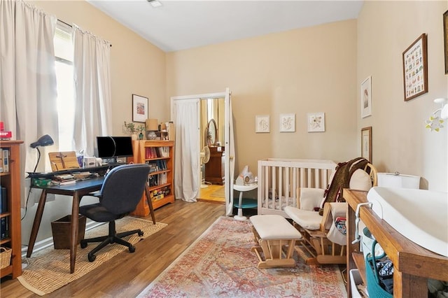 bedroom featuring an office area and wood finished floors