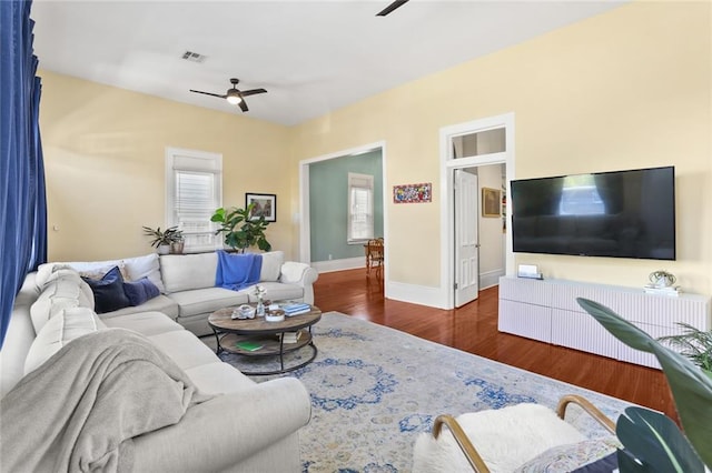 living area with visible vents, baseboards, wood finished floors, and a ceiling fan