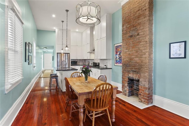 dining space with dark wood finished floors, a fireplace, baseboards, and a towering ceiling