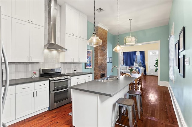 kitchen featuring dark countertops, wall chimney range hood, double oven range, decorative backsplash, and a sink