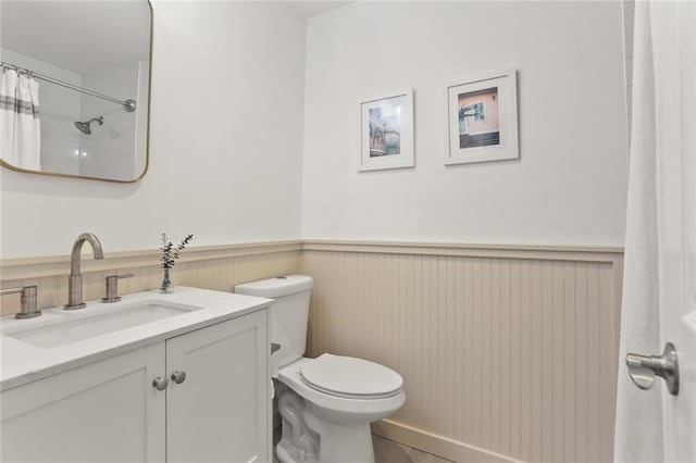 full bath featuring a wainscoted wall, toilet, curtained shower, tile patterned flooring, and vanity