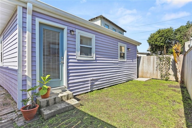 exterior space with entry steps, a lawn, and fence