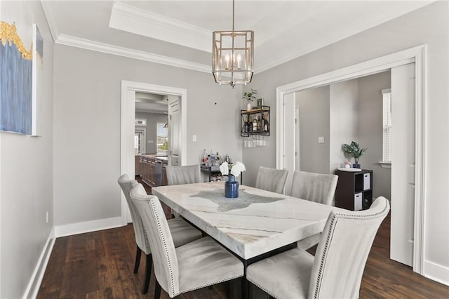 dining space featuring a tray ceiling, baseboards, dark wood-style flooring, and ornamental molding