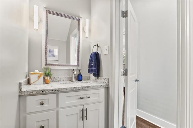 bathroom with baseboards, wood finished floors, and vanity