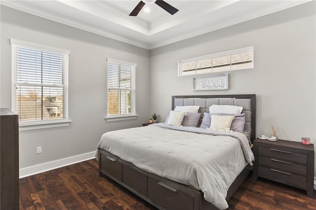 bedroom featuring a ceiling fan, baseboards, a tray ceiling, ornamental molding, and dark wood-type flooring