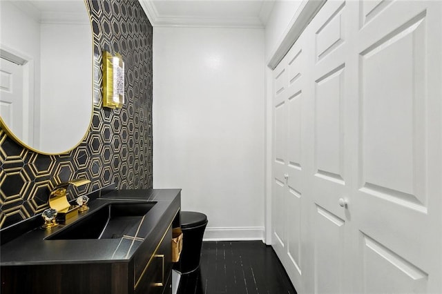 bathroom with vanity, wood finished floors, baseboards, ornamental molding, and toilet