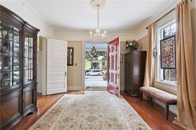 entryway featuring baseboards, an inviting chandelier, wood finished floors, and crown molding