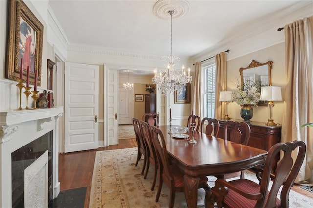 dining room with an inviting chandelier, crown molding, wood finished floors, and a high end fireplace