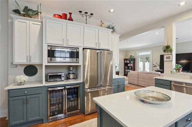 kitchen with stainless steel appliances, beverage cooler, white cabinets, and light countertops