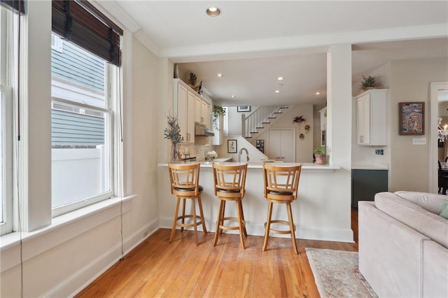 kitchen featuring plenty of natural light, a breakfast bar, light wood-style flooring, and light countertops