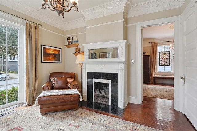 sitting room featuring a high end fireplace, a notable chandelier, ornamental molding, and wood finished floors