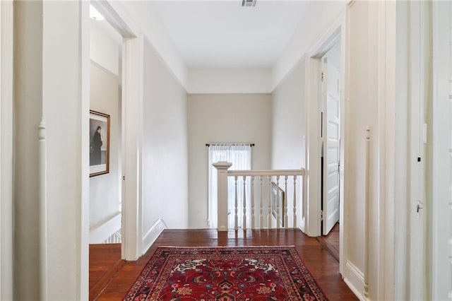 hall with dark wood finished floors, an upstairs landing, and visible vents