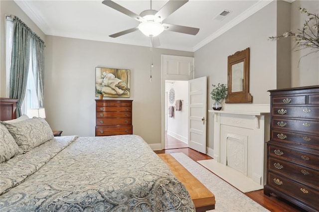 bedroom featuring visible vents, wood finished floors, a ceiling fan, and ornamental molding