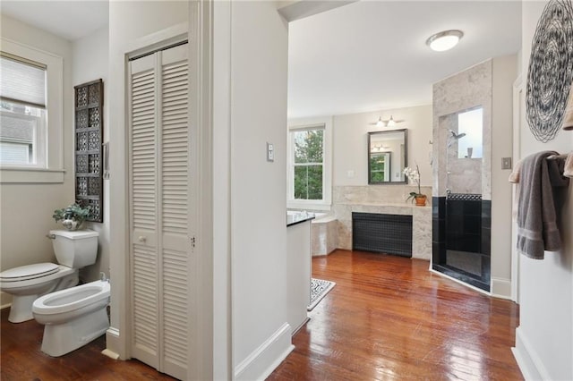 bathroom with a closet, a stall shower, a bidet, and hardwood / wood-style flooring