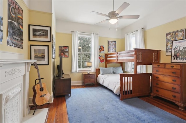 bedroom featuring ceiling fan, baseboards, multiple windows, and wood finished floors