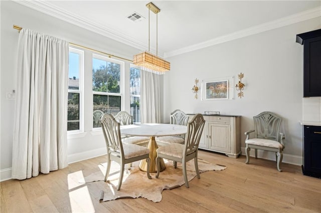 dining room with light wood-type flooring, baseboards, visible vents, and crown molding