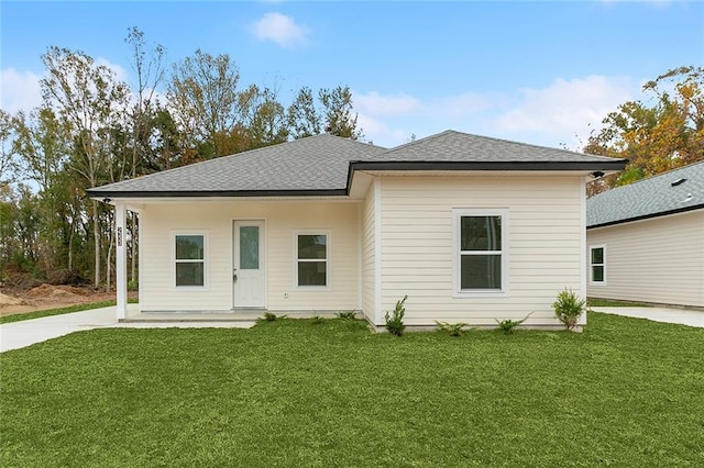 rear view of property with a shingled roof and a yard