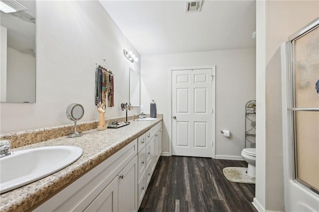 full bath featuring a sink, visible vents, a shower with door, and wood finished floors