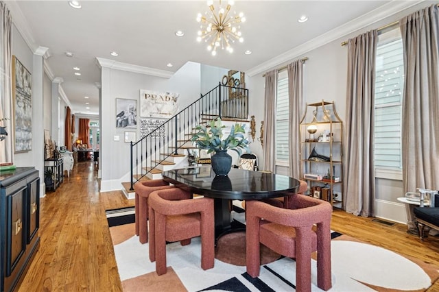 dining room featuring a notable chandelier, stairway, light wood-style floors, and ornamental molding