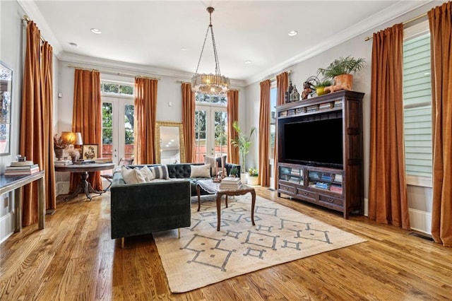 living area with visible vents, french doors, crown molding, and wood finished floors