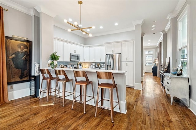 kitchen with backsplash, light countertops, a peninsula, stainless steel appliances, and white cabinetry