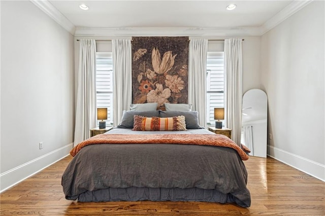 bedroom featuring baseboards, wood finished floors, and ornamental molding