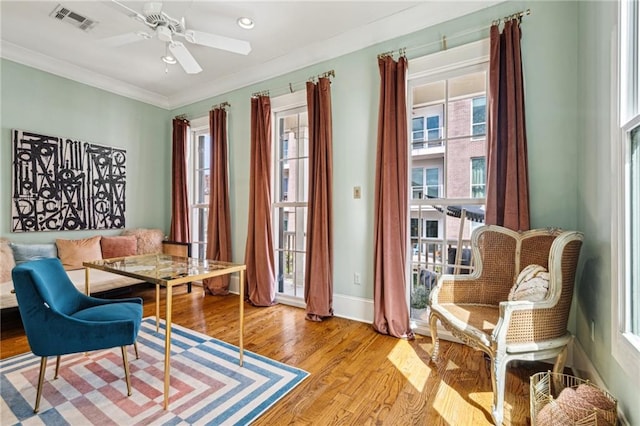 sitting room with visible vents, a healthy amount of sunlight, ornamental molding, and wood finished floors