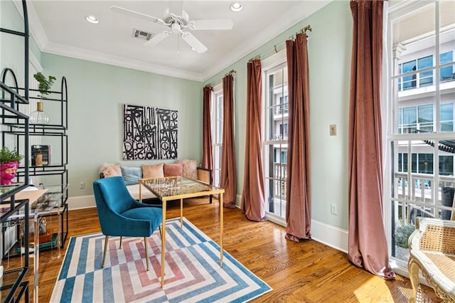 sitting room featuring visible vents, ornamental molding, baseboards, and wood finished floors