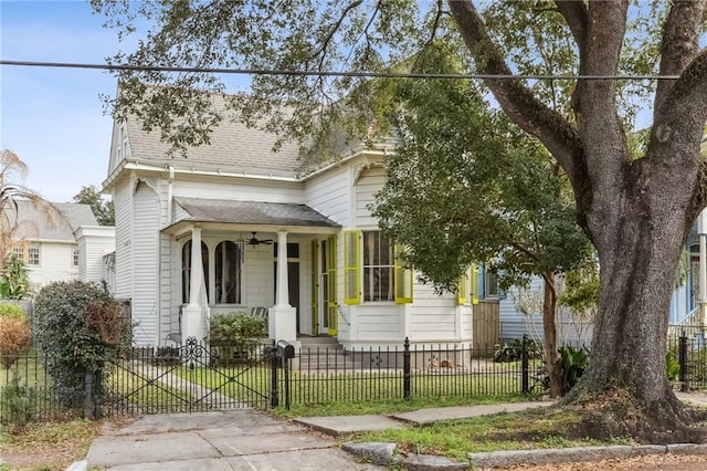 view of front of home with a gate, a fenced front yard, a ceiling fan, and a shingled roof