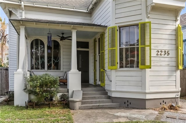 doorway to property with covered porch, roof with shingles, and a ceiling fan